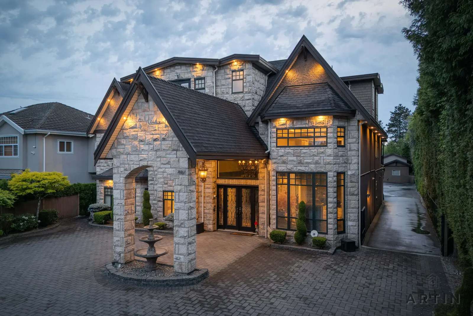 Stone house with a lit entry and fountain in Richmond
